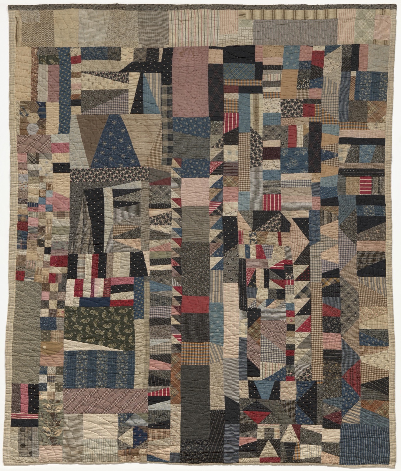 A scrap quilt pieced from shirting plaids, stripes, and paisleys in faded blues, reds, and creams — irregular strips, hand-quilted.